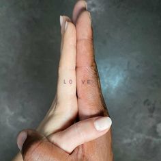 two hands holding each other with the word love tattooed on their fingers