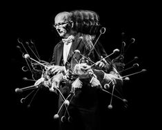 a black and white photo of a man in a suit with many strings on his hands