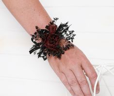 a woman's hand with a bracelet made out of flowers and leaves on it