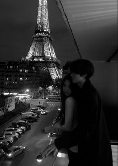 a man and woman standing next to each other in front of the eiffel tower