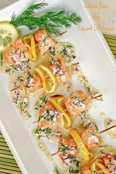 a white plate topped with shrimp and lemons on skewers next to a lemon wedge