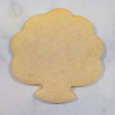 a cookie shaped like a flower sitting on top of a white countertop next to a piece of paper