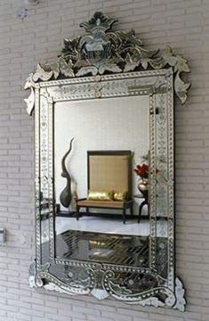 a large mirror hanging on the side of a brick wall next to a vase with flowers