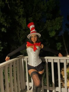 a woman dressed up as a cat in the hat posing on a porch with her legs crossed