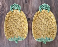 two yellow and green pineapple shaped plates sitting on top of a wooden table