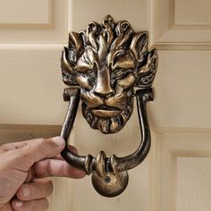 a hand holding a door handle with a lion head on it