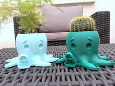 two plastic octopus planters sitting on top of a table next to a potted cactus