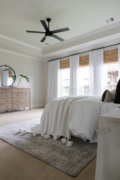 a bedroom with a bed, dresser and ceiling fan in the middle of the room