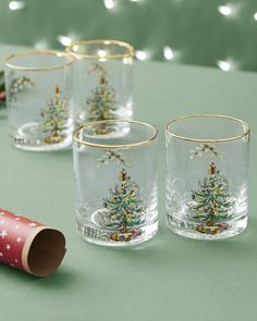 three glass cups sitting on top of a table next to a christmas tree candle holder