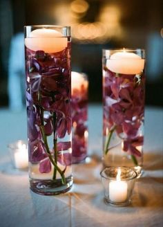 two vases with flowers and candles on a table