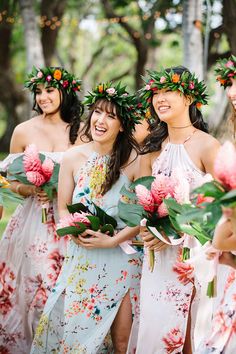 a group of women standing next to each other holding flowers and greenery in their hair