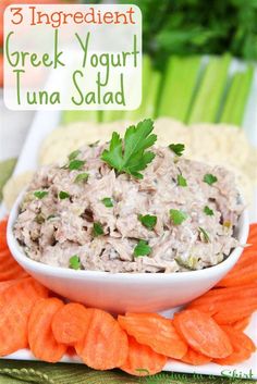 a bowl filled with tuna salad on top of carrots and celery sticks