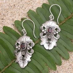 Elaborate and elegant Giri Tasmana's dangle earrings are perfect for a fancy dinner party. The Balinese artisan uses sterling silver to hand craft the floral motif centering each earring with a faceted garnet stone for an unexpected pop of radiant color. Ornate Sterling Silver Chandelier Earrings For Formal Occasions, Ornate Sterling Silver Chandelier Earrings For Formal Events, Elegant Garnet Drop Earrings, Ornate Sterling Silver Chandelier Earrings As Gift, Elegant Garnet Earrings, Formal Dangle Garnet Earrings, Formal Garnet Dangle Earrings, Handmade Silver Chandelier Earrings For Formal Occasions, Silver Handmade Chandelier Earrings For Formal Occasions