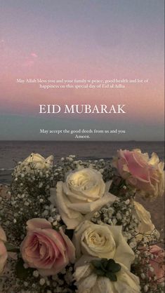 a bouquet of flowers sitting on top of a wooden table next to the ocean with an inspirational quote about eid mubarak