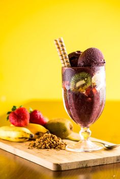 a glass filled with fruit on top of a wooden cutting board