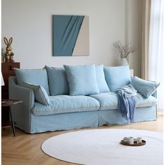 a blue couch sitting on top of a wooden floor next to a white round rug