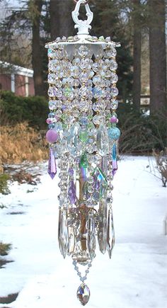 a wind chime hanging from the side of a snow covered yard with trees in the background