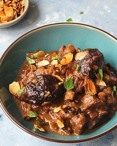 a bowl filled with meat and nuts on top of a table