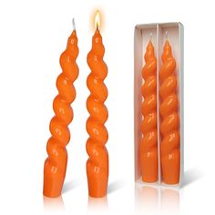 two orange candles are in a box and one is turned on the side with a single candle sticking out of it