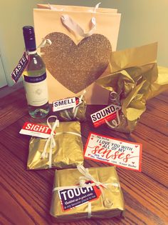 some wine and other items are sitting on a table next to a heart shaped bag