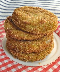 some fried food on a white plate with a red and white checkered table cloth