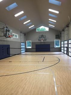 an indoor basketball court with hard wood flooring and skylights on the sidelines