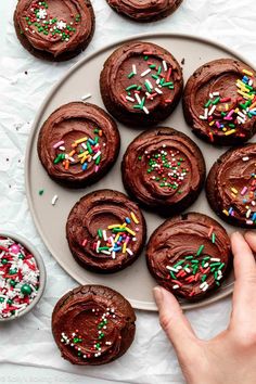 chocolate cookies with frosting and sprinkles on a plate