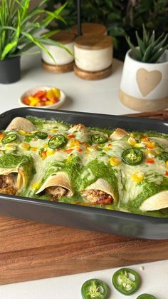 a pan filled with food sitting on top of a wooden table next to green peppers