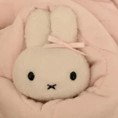 a white stuffed animal in a pink blanket