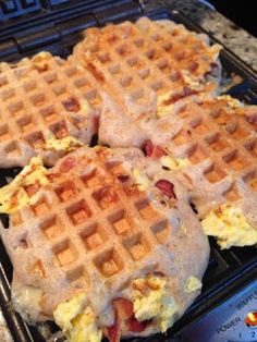 three waffles with eggs and bacon on them are sitting on a pan in the oven