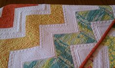 two quilts are laying next to each other on a table top with a wooden surface in the background