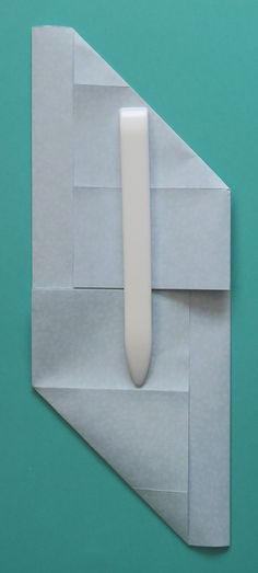 a piece of paper with a white object sticking out of it's corner on a green background