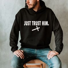 "Introducing the epitome of faith-infused fashion: our \"Just Trust Him\" hoodie. This remarkable piece seamlessly blends iconic design with a profound message, embodying the spirit of unwavering trust and belief, all while paying homage to the renowned sportswear emblem. Crafted with meticulous attention to detail, this hoodie boasts a striking cross motif in place of the traditional swoosh, creating a harmonious fusion of sacred symbolism and contemporary style. The \"Just Trust Him\" design serves as a visual reminder of the power of faith, resilience, and the journey towards greatness. Step into comfort and purpose with our premium-quality hoodie, enveloping you in a cocoon of warmth and softness. Expertly crafted fabrics ensure a luxurious feel against your skin, while the eye-catchin Ohio State Shirts, Christian Apparel, Christian Cross, Funny T, Vintage Tshirts, The Journey, Cool Shirts, Funny Tshirts, Contemporary Style