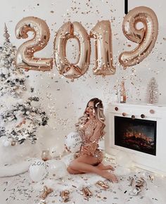 a woman sitting on the floor in front of balloons and confetti