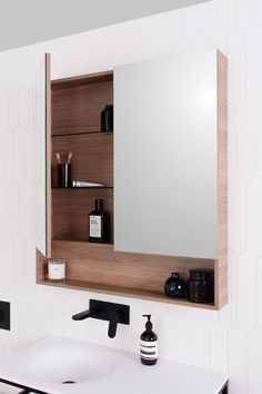 a bathroom with a sink, mirror and shelves on the wall next to each other