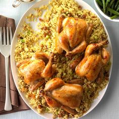 a white plate topped with chicken and rice next to two silverware on a table