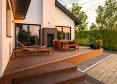 an outdoor deck with lounge chairs and wooden steps leading up to the front of a house