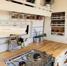 a stove top oven sitting inside of a kitchen next to a wooden cutting board with pots and pans on it