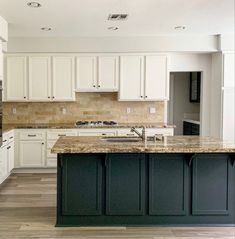 a kitchen with white cabinets and marble counter tops