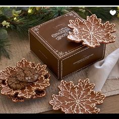 some cookies are sitting on a table next to a box and christmas tree branch decorations