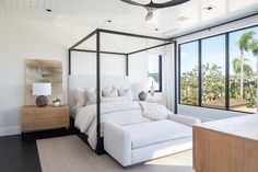 a bedroom with white furniture and large windows