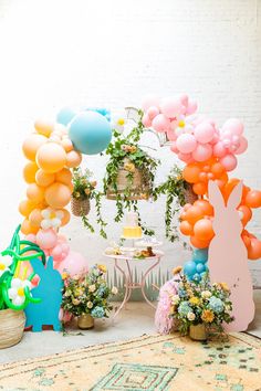 an assortment of balloons and flowers on display in front of a white brick wall,