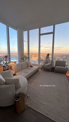 a man sitting on a couch in a living room next to a large window overlooking the city