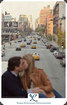 a man and woman kissing in the middle of a city street with taxi cabs