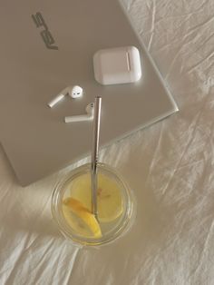 an apple airpods sitting on top of a table next to a glass with lemon slices in it