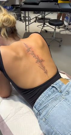 a woman laying on top of a bed with a tattoo on her back