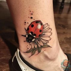 a ladybug tattoo on the ankle that is sitting on top of a woman's leg