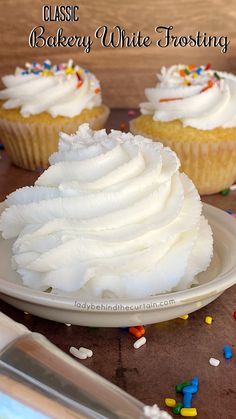 cupcakes with white frosting and sprinkles on a plate