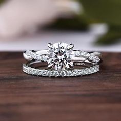 an engagement ring and wedding band set on top of a wooden table