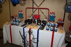 a table topped with lots of candy and sports themed items on top of a white table cloth